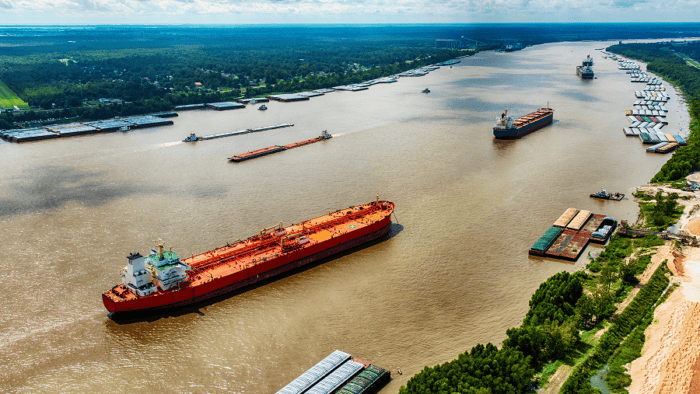 Three commercial vessels navigating a narrow waterway channel