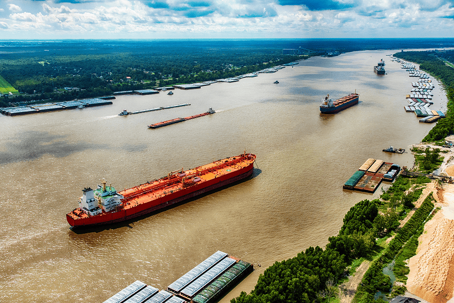 Three commercial vessels navigating a narrow waterway channel