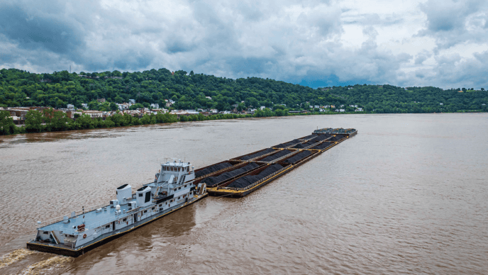 A commercial tugboat pushing a cargo barge along an inland waterway