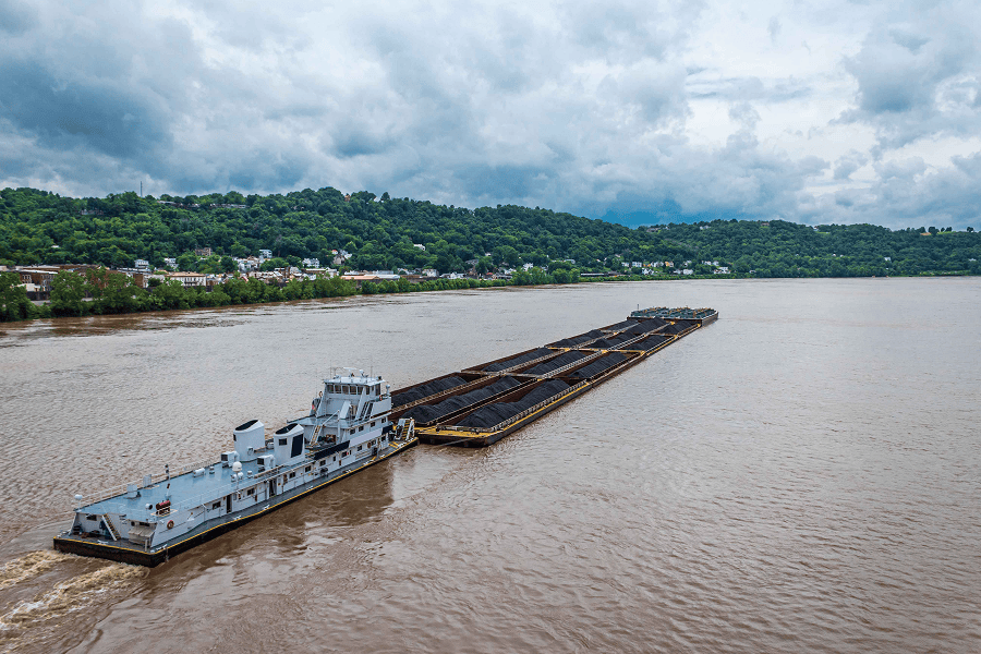 A commercial tugboat pushing a cargo barge along an inland waterway