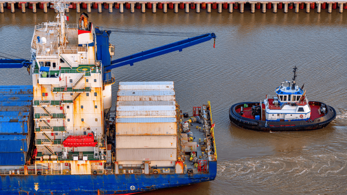 A commercial tugboat pushing a cargo barge along an inland waterway