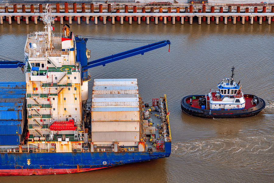A commercial tugboat pushing a cargo barge along an inland waterway