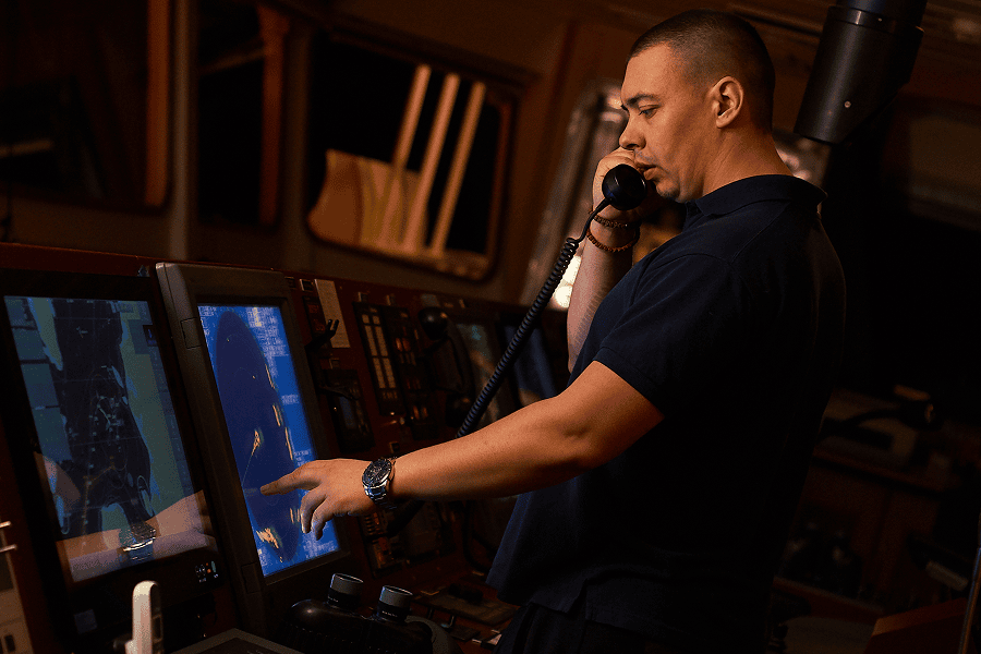 A male maritime crew member looking at digital navigation routes