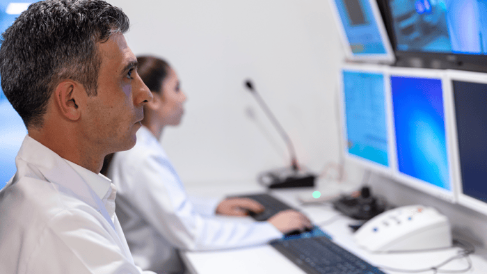 A control operator tracking real-time vessel fleet data and maritime routing across multiple computer monitors.