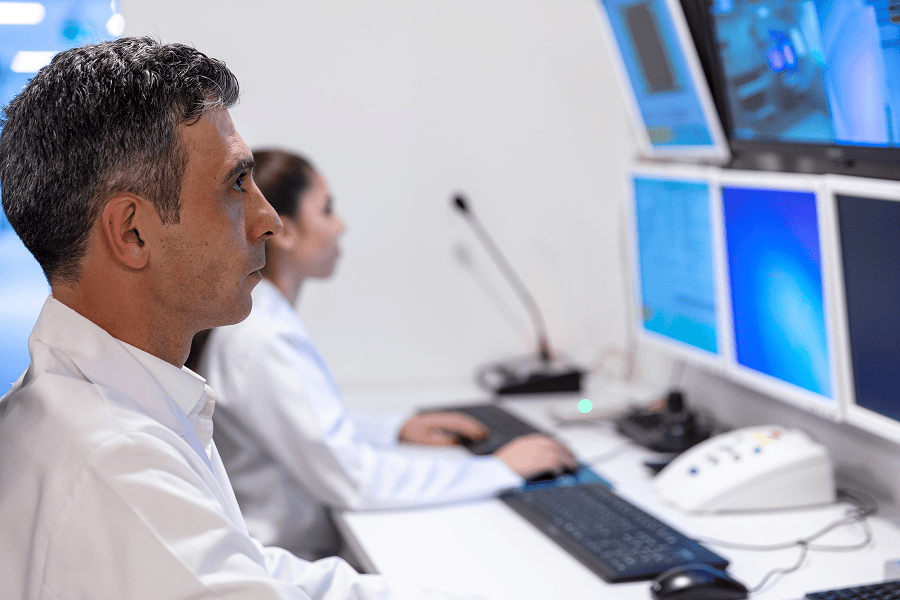 A control operator tracking real-time vessel fleet data and maritime routing across multiple computer monitors.