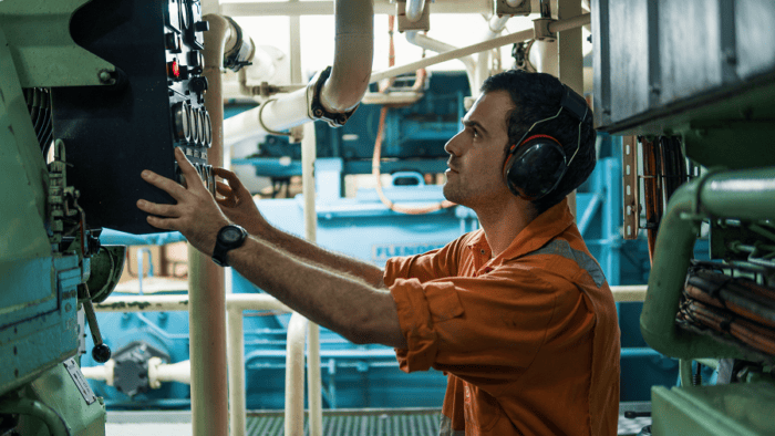 A maritime control room operator looking at an electronic control board