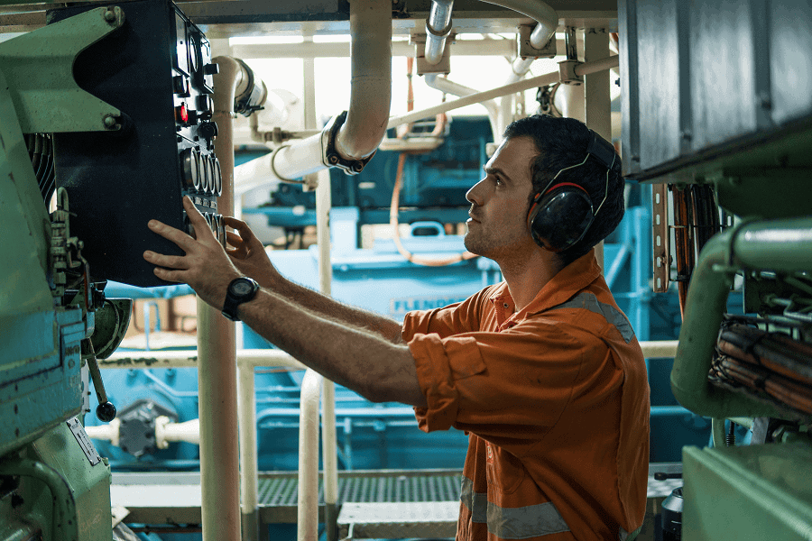 A maritime control room operator looking at an electronic control board