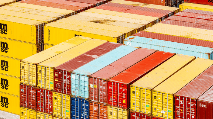 Rows of multicolored shipping containers neatly stacked at a commercial port terminal.