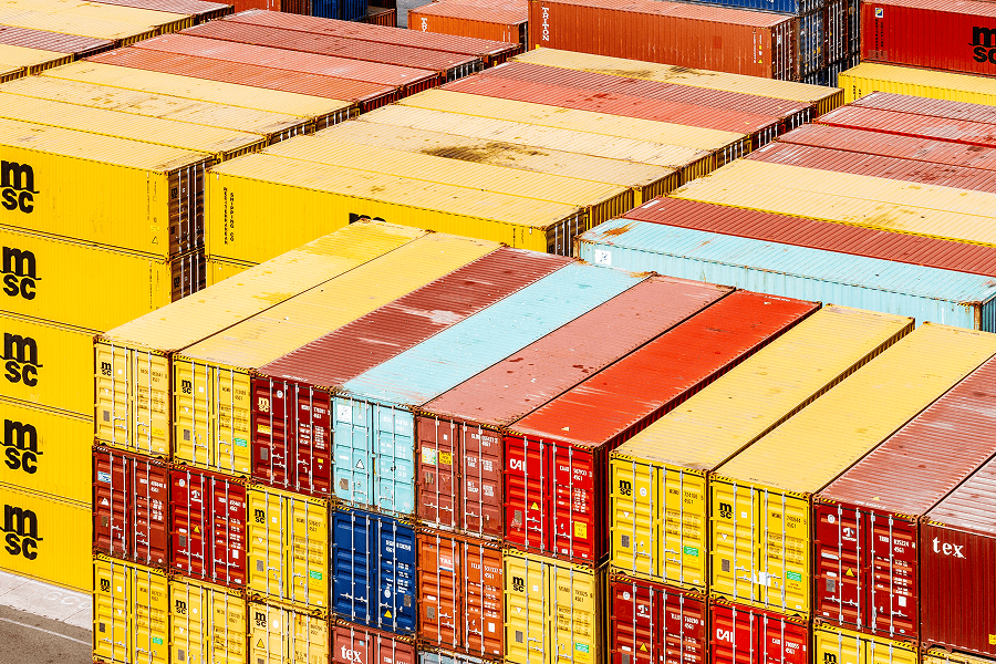 Rows of multicolored shipping containers neatly stacked at a commercial port terminal.