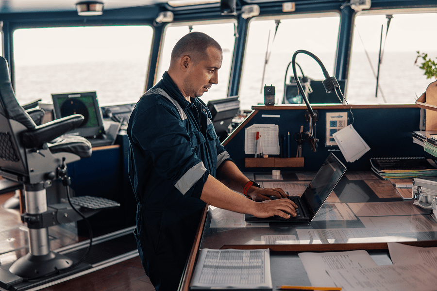 A maritime ship officer using a laptop inside the bridge control room