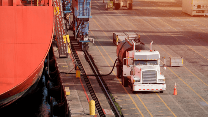 A fuel truck refueling a maritime vessel at a port terminal