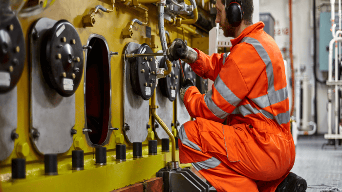 Maritime engineer in an engine room conducting safety inspections and mechanical maintenance