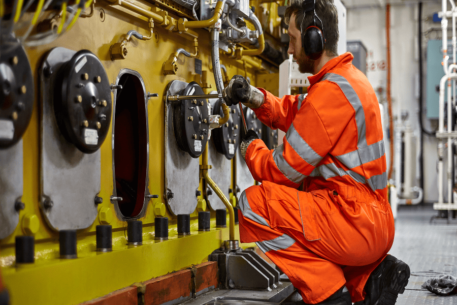 Maritime engineer in an engine room conducting safety inspections and mechanical maintenance
