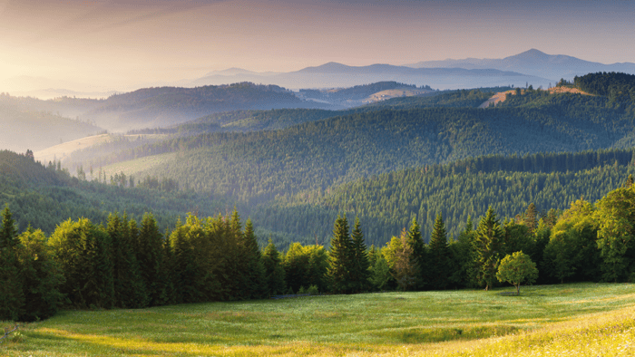 A scenic view of rolling mountains and bright green hills