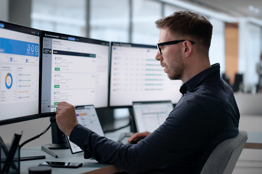 An analyst checking a software data dashboard on multiple screens