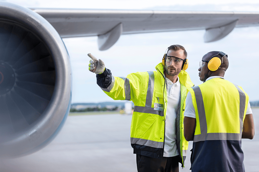 Two airport workers discussing near engine