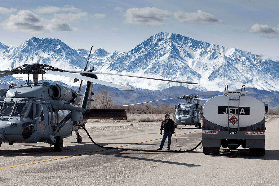 Helicopters refueling near snowy mountains.