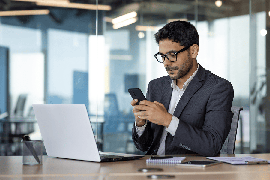 Businessman focused on phone at desk.