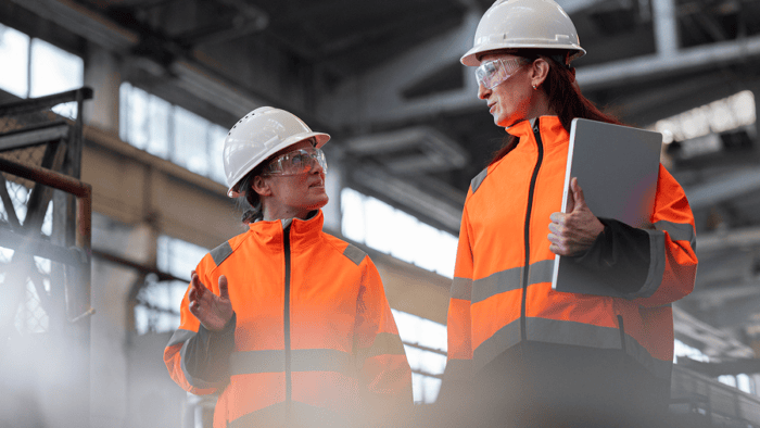 Two women discussing in safety gear.
