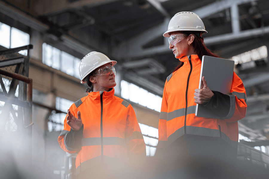 Two women discussing in safety gear.