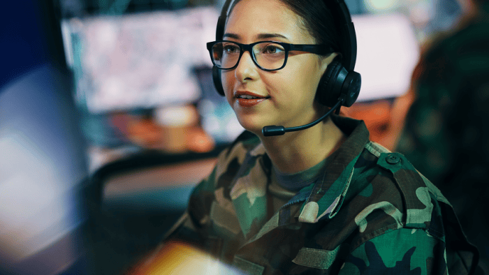 A woman wearing a headset working inside an army command center
