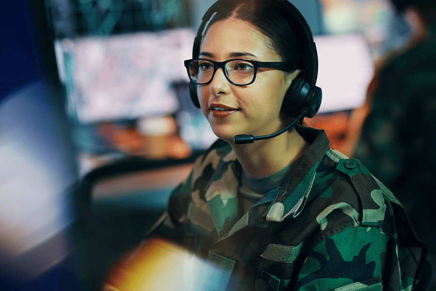 A woman wearing a headset working inside an army command center