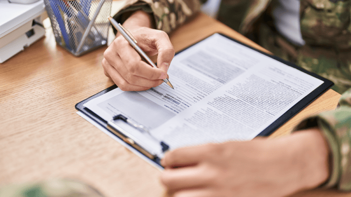 An army soldier signing an official contract at an office desk