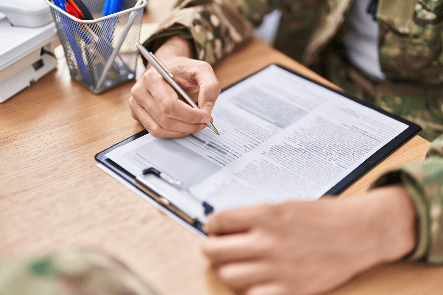An army soldier signing an official contract at an office desk