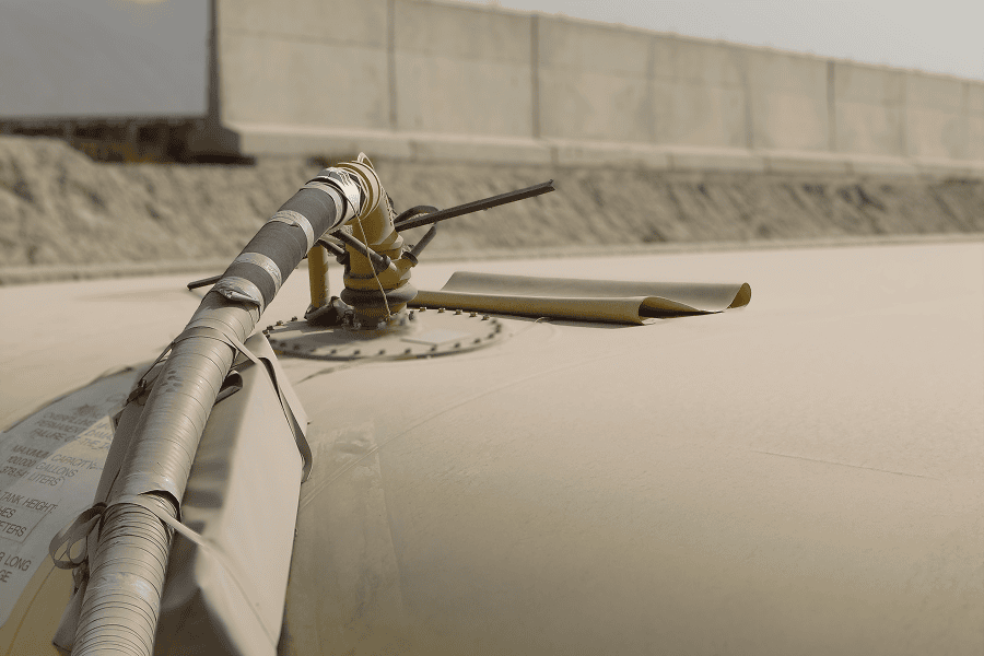 Industrial storage tank with monitoring equipment and piping installed along the top surface.