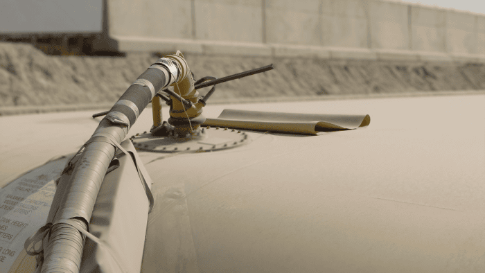 Industrial storage tank with monitoring equipment and piping installed along the top surface.