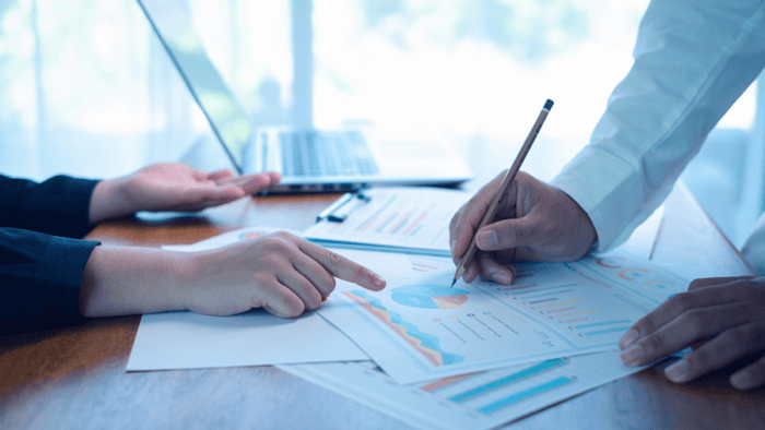 Hands discussing financial reports and charts.