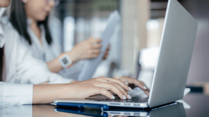 Women collaborating over laptop and documents.