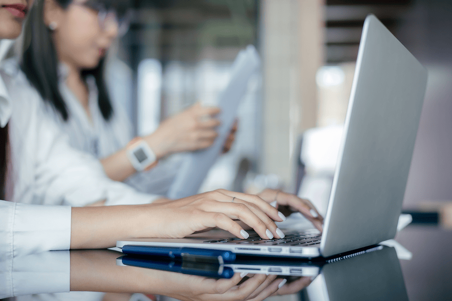 Women collaborating over laptop and documents.
