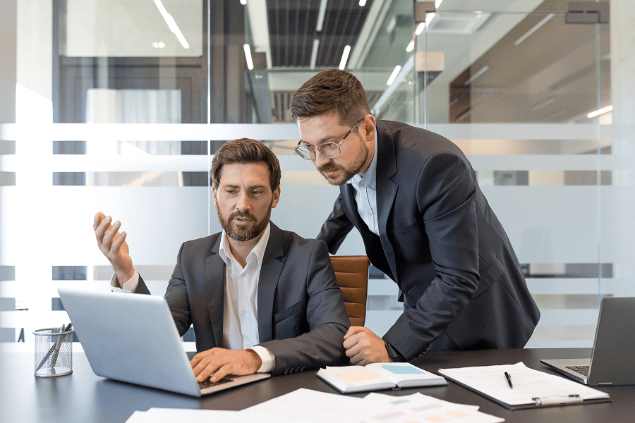 Two businessmen discussing strategy over laptop.
