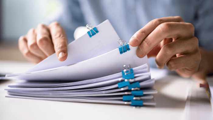 Person organising documents with clips.