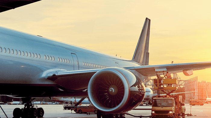 Airplane at sunset with maintenance crew.
