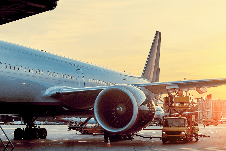 Airplane at sunset with maintenance crew.