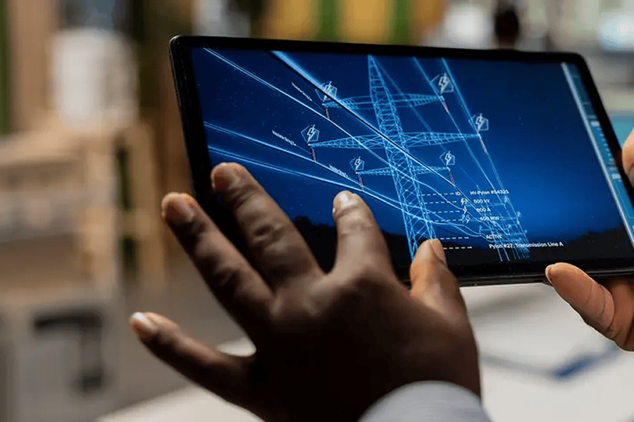 Person using a tablet displaying a digital model of an electrical transmission tower and smart grid infrastructure.