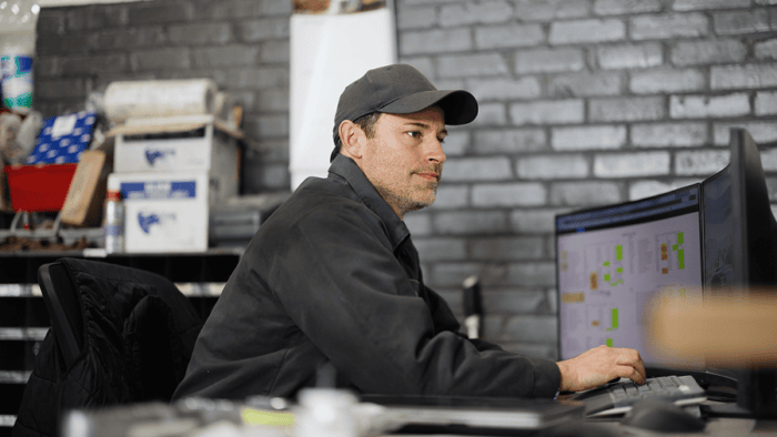 man with hat looking at computer screen