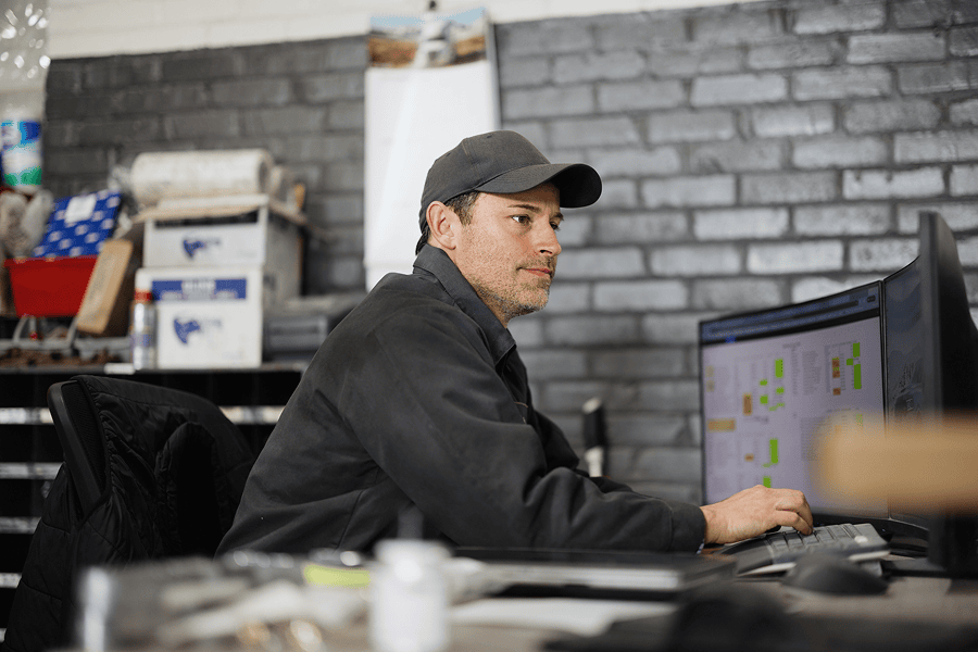 man with hat looking at computer screen