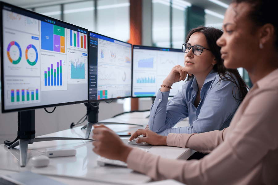 Women analysing data on multiple screens.