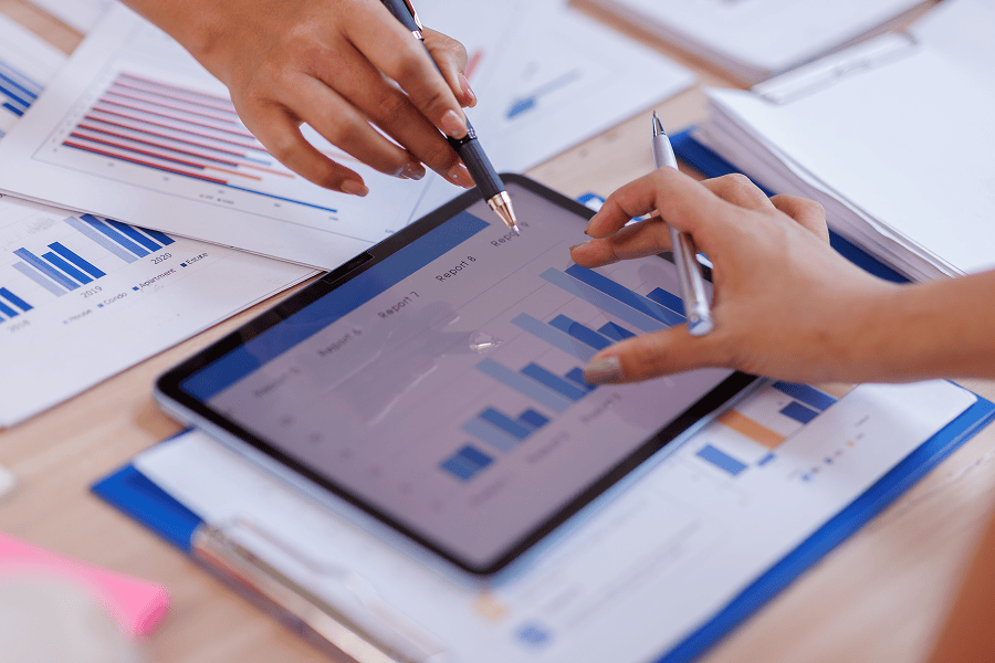 Hands analysing financial graphs on tablet.