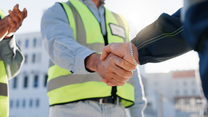Two people shaking hands outdoors.