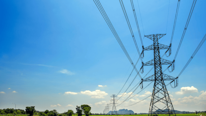 Power lines over green farmland and sky.