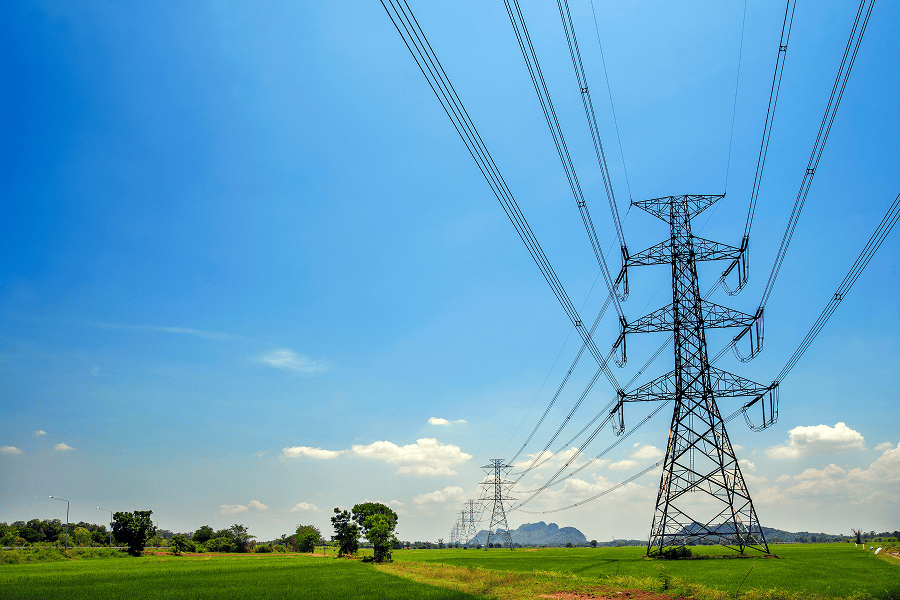 Power lines over green farmland and sky.