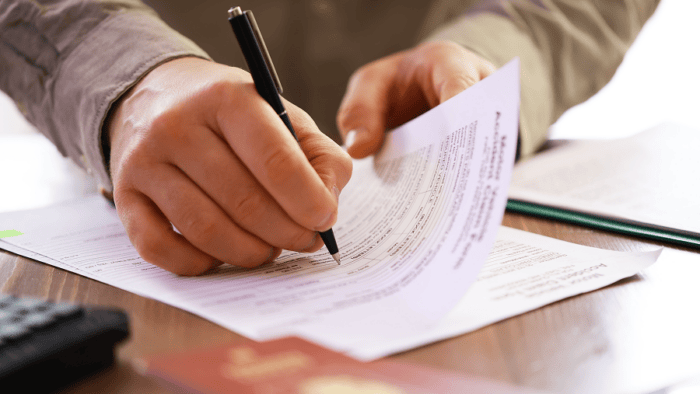 Hands signing a document with pen.