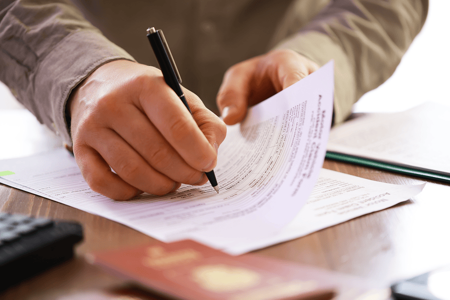 Hands signing a document with pen.