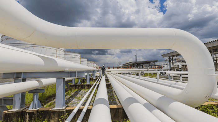 Pipes and storage tanks under cloudy sky.