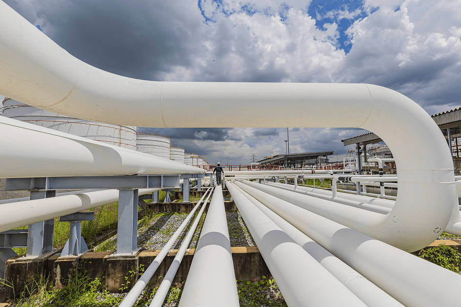 Pipes and storage tanks under cloudy sky.