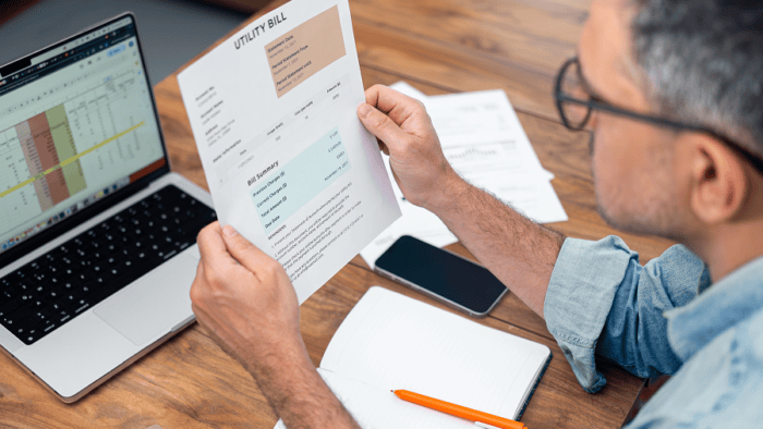Man reviewing utility bill at desk.